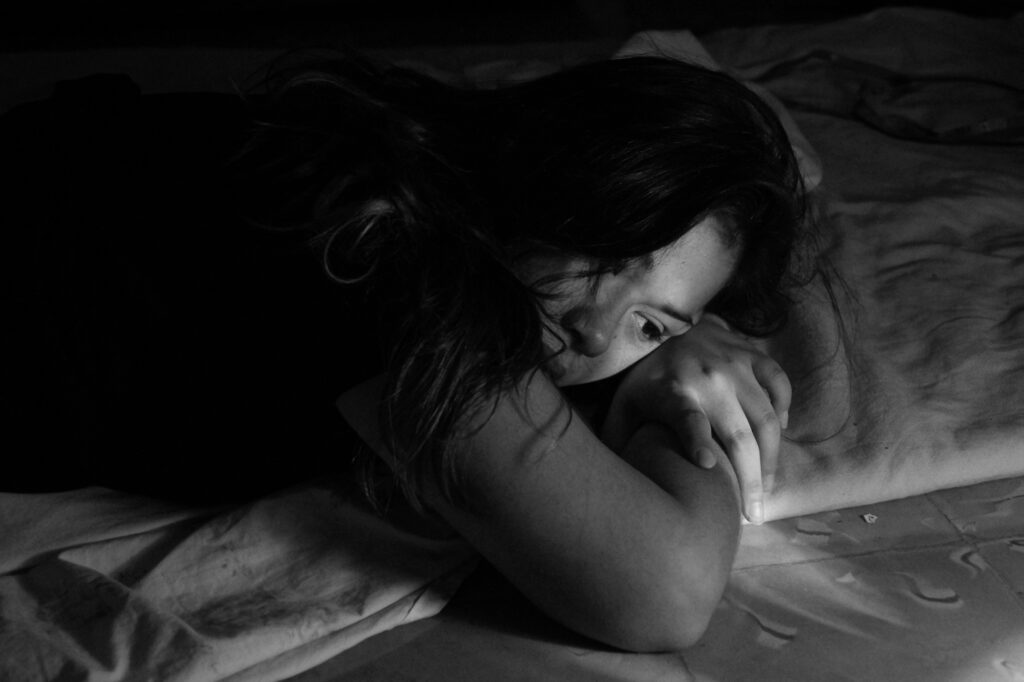 Ritratto di una giovane studentessa appoggiata sul letto in un momento di riflessione, copertina per la presentazione della piattaforma di segnalazione bullismo nelle scuole Butterfly.