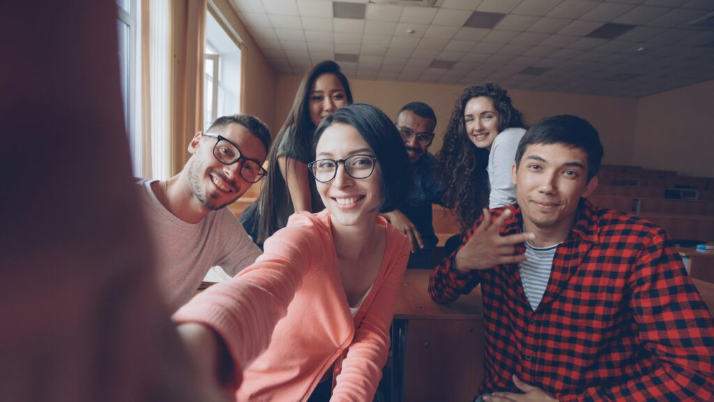 Un gruppo di studenti che si fa un selfie in classe sorridendo, rappresentando il ritorno alla fiducia e alla sicurezza nel contesto educativo.